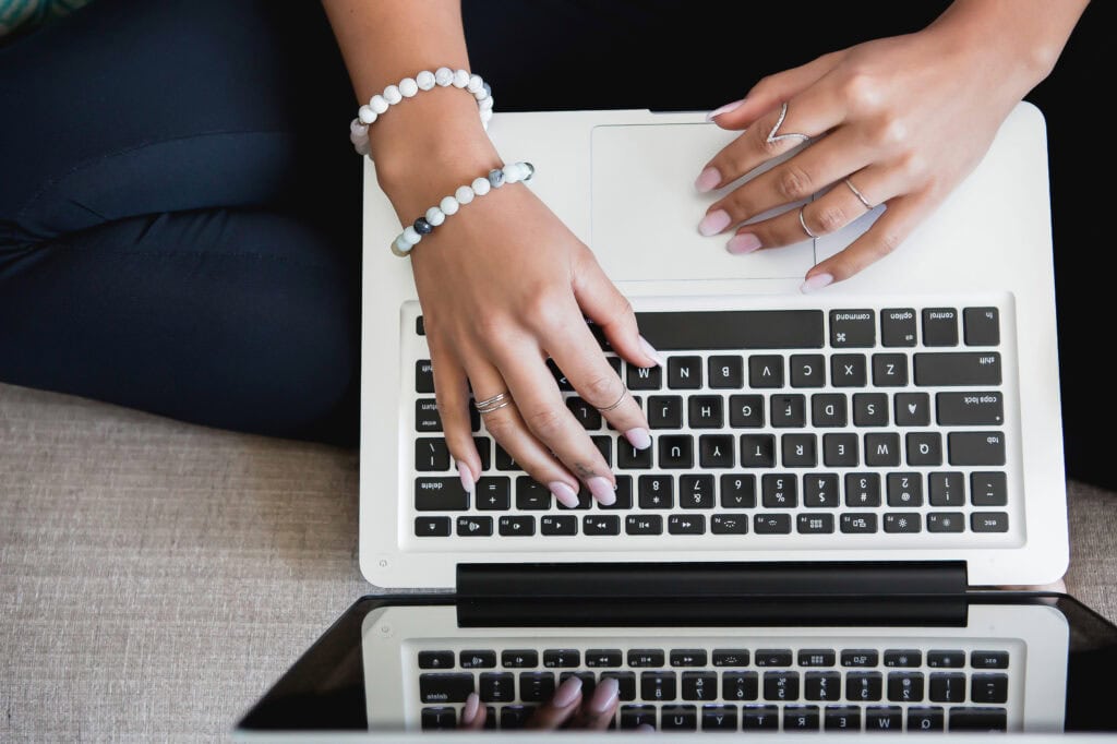 Overhead shot of a woman's hands typing on a laptop.