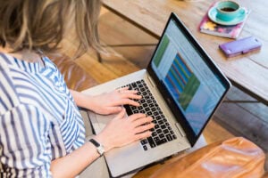 Woman typing on a laptop which shows a colour coded spreadsheet