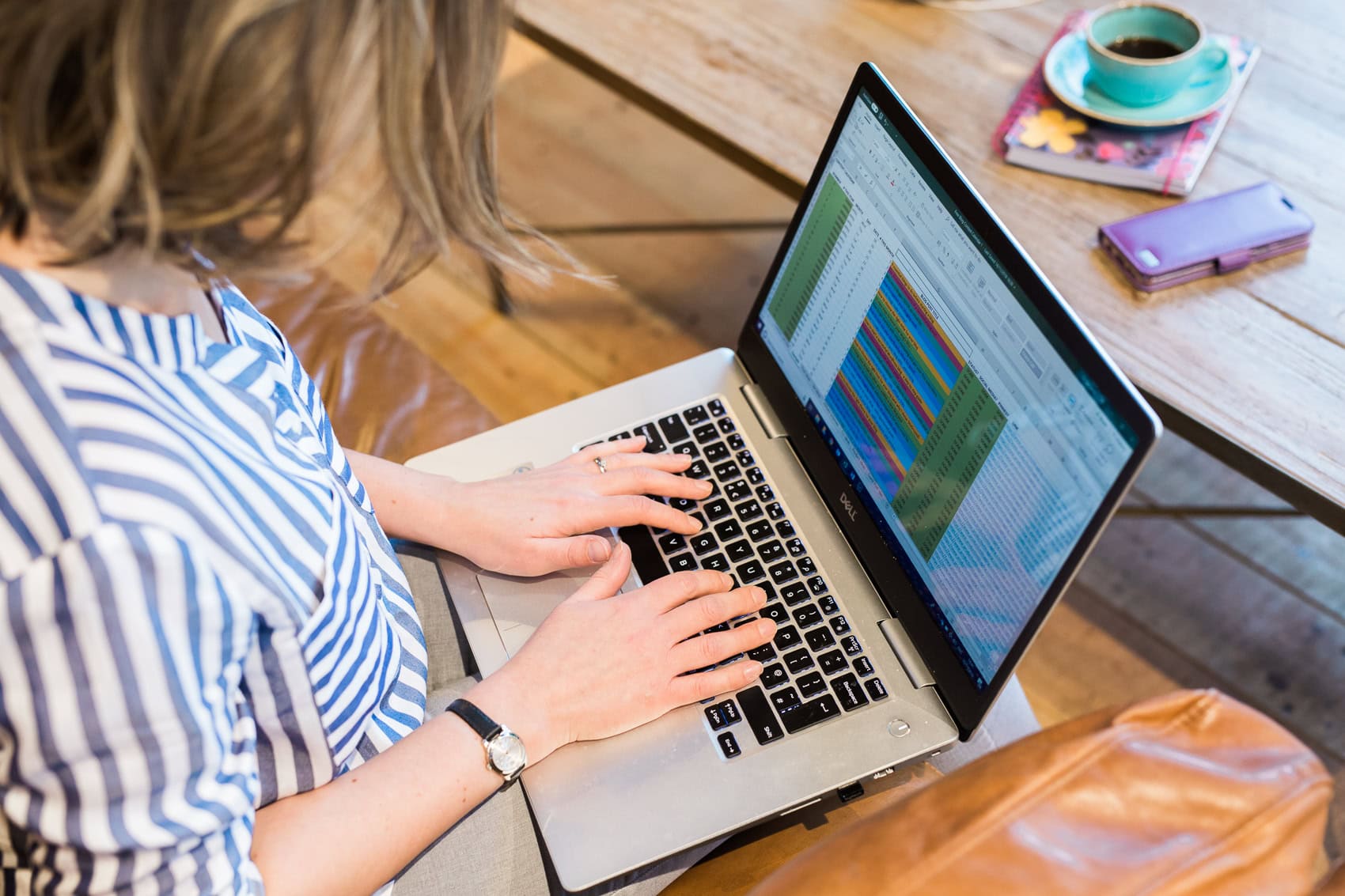 Woman typing on a laptop which shows a colour coded spreadsheet